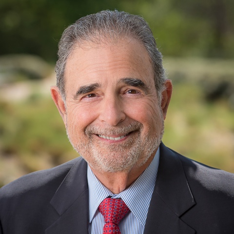 man wearing a blue suit with a red tie smiling