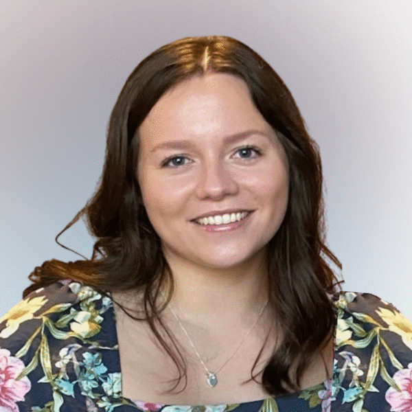 woman with brown hair wearing a floral dress smiling