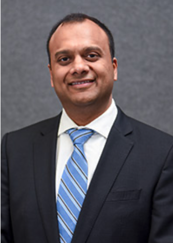 indian man in a suit and blue tie smiling