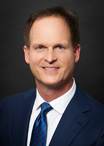 Quint Barefoot headshot. Man in a suit smiling.