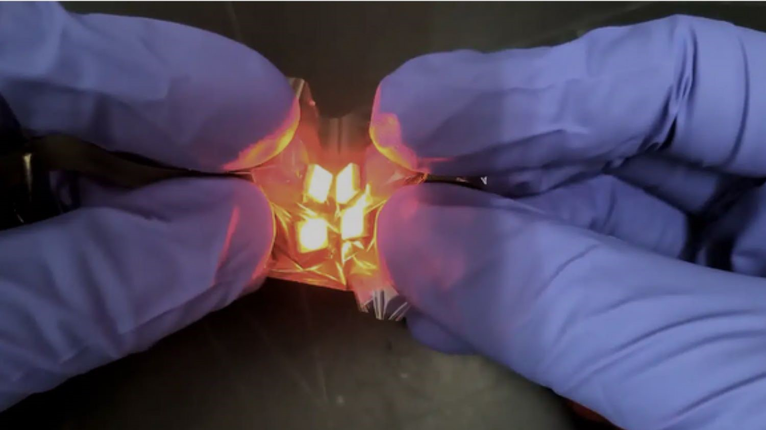 Flexible metal oxide thin film with embedded LEDs being held and crumpled