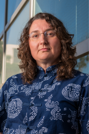 woman with dark hair, glasses, and a blue shirt