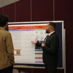 man speaking to another person about his research poster