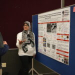 woman speaking to another person about her research poster