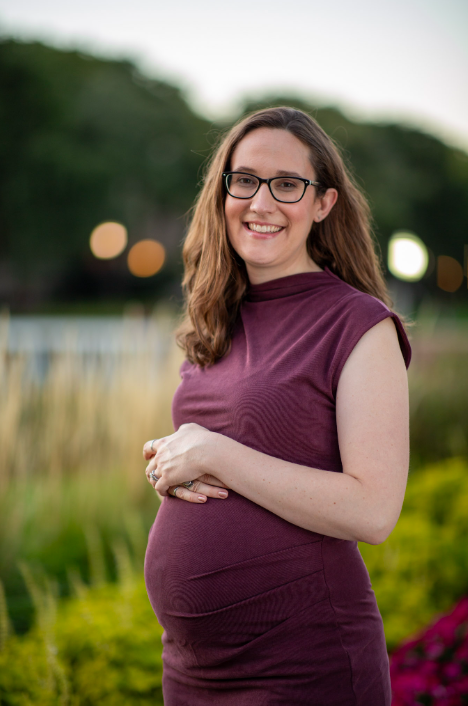 pregnant woman with dark hair, wearing glasses and a purple dress