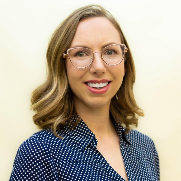 blonde woman wearing glasses and a blue shirt smiling