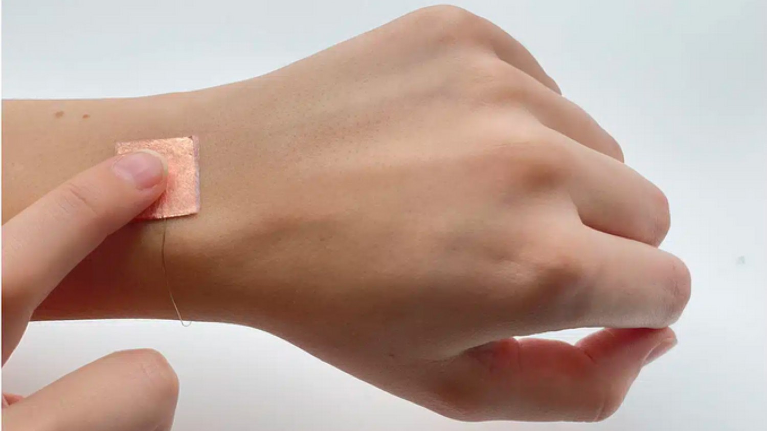 Photograph depicts a user tapping a flexible, wearable triboelectric device that generates power when worn.