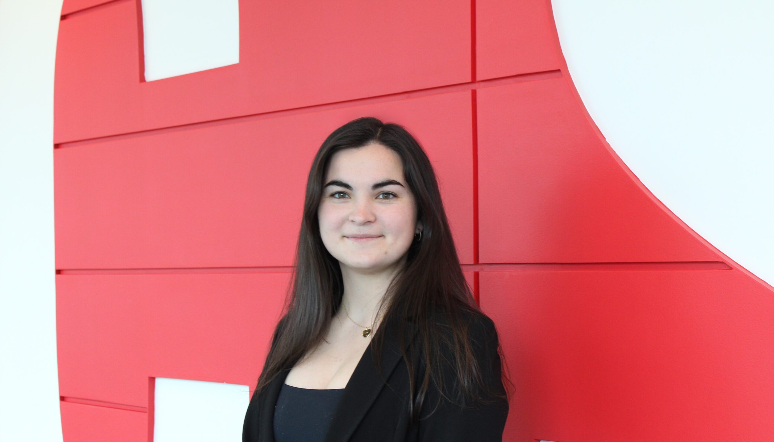 Naomi Bouedo posing in front of the NC State wall in Talley Student Union.