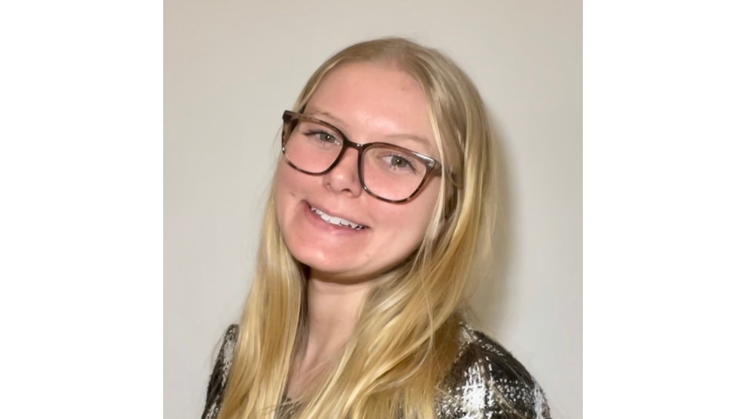 blonde woman wearing plaid shirt and black glasses smiling