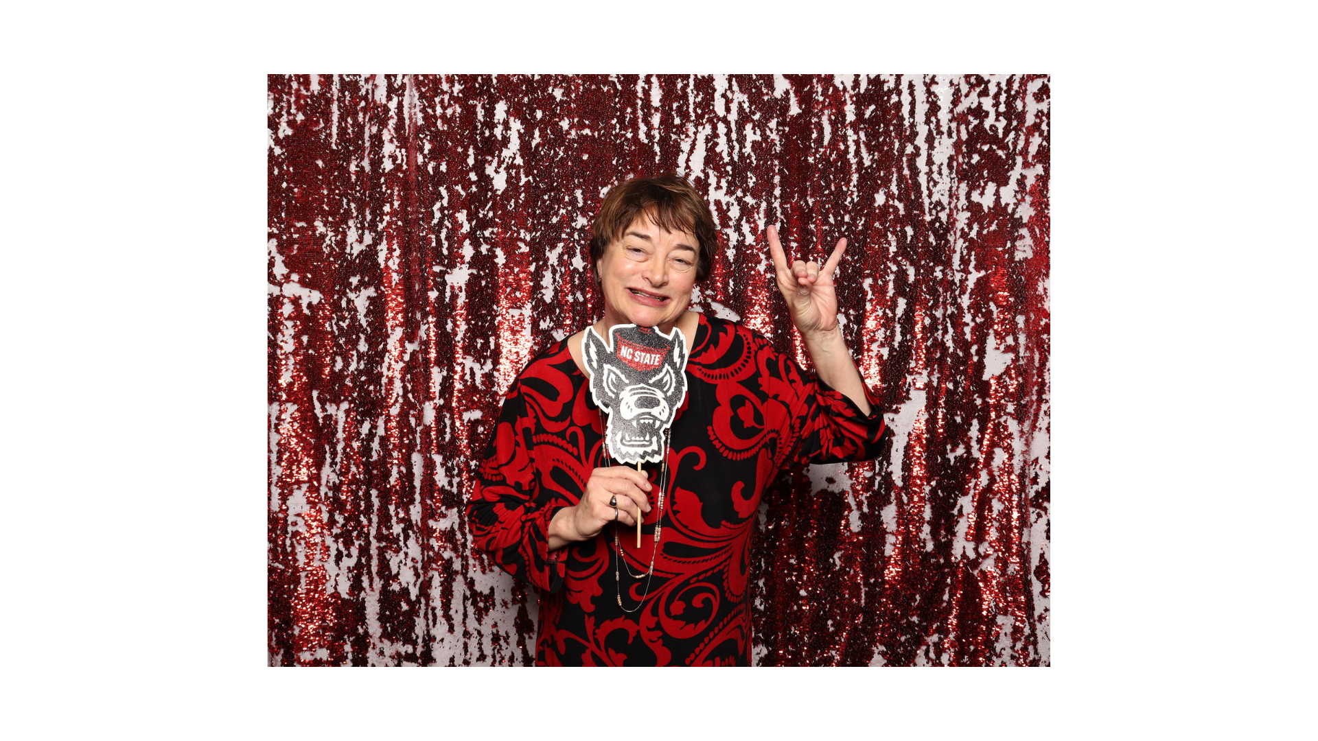 Lisa Bullard holding a Mr. Wuf sign in front of a sparkly background