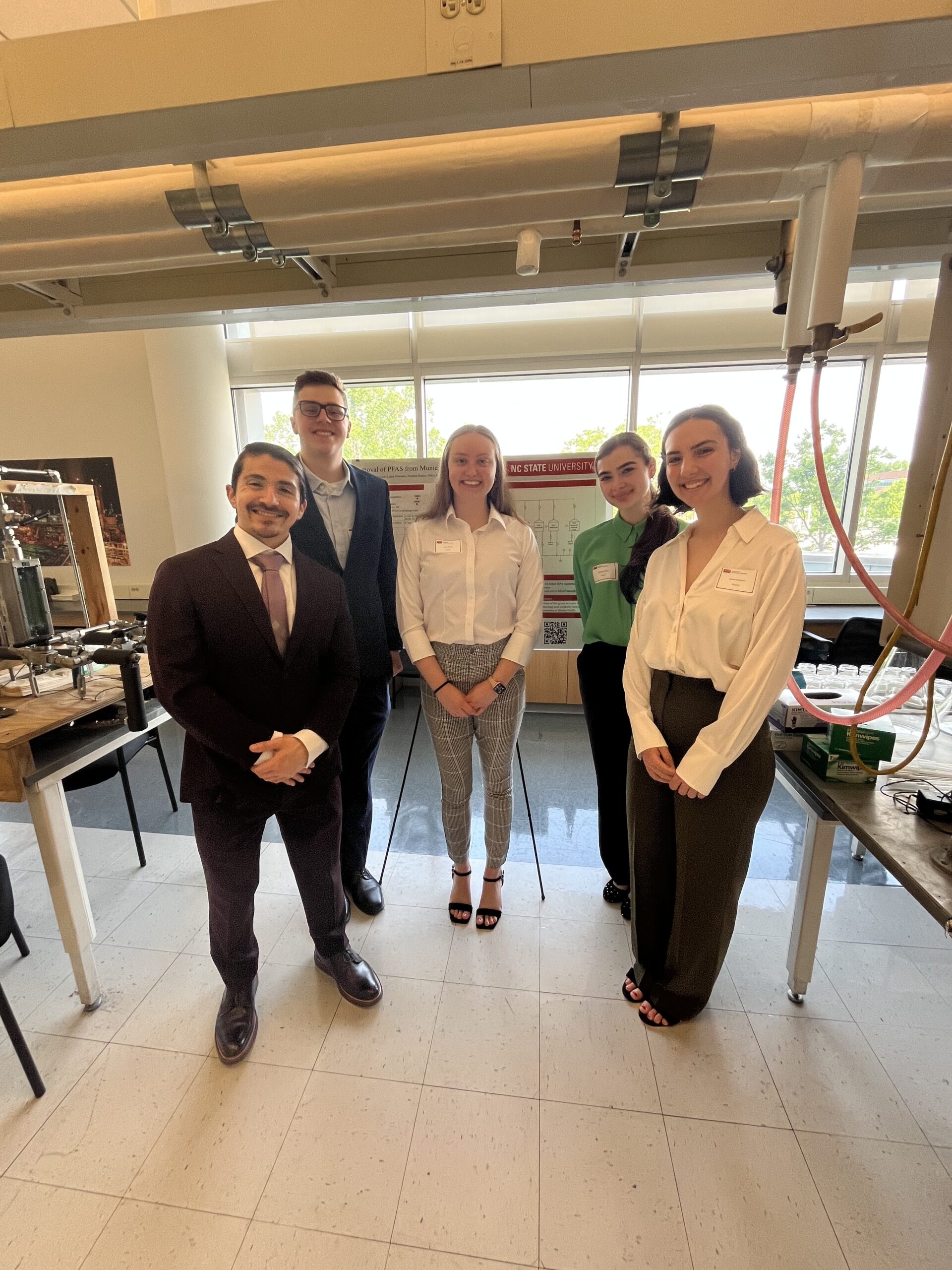 senior design group smiling in front of their poster. April 2025.