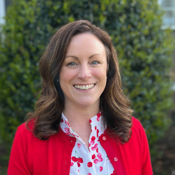 a woman with dark hair wearing a red cardigan smiling