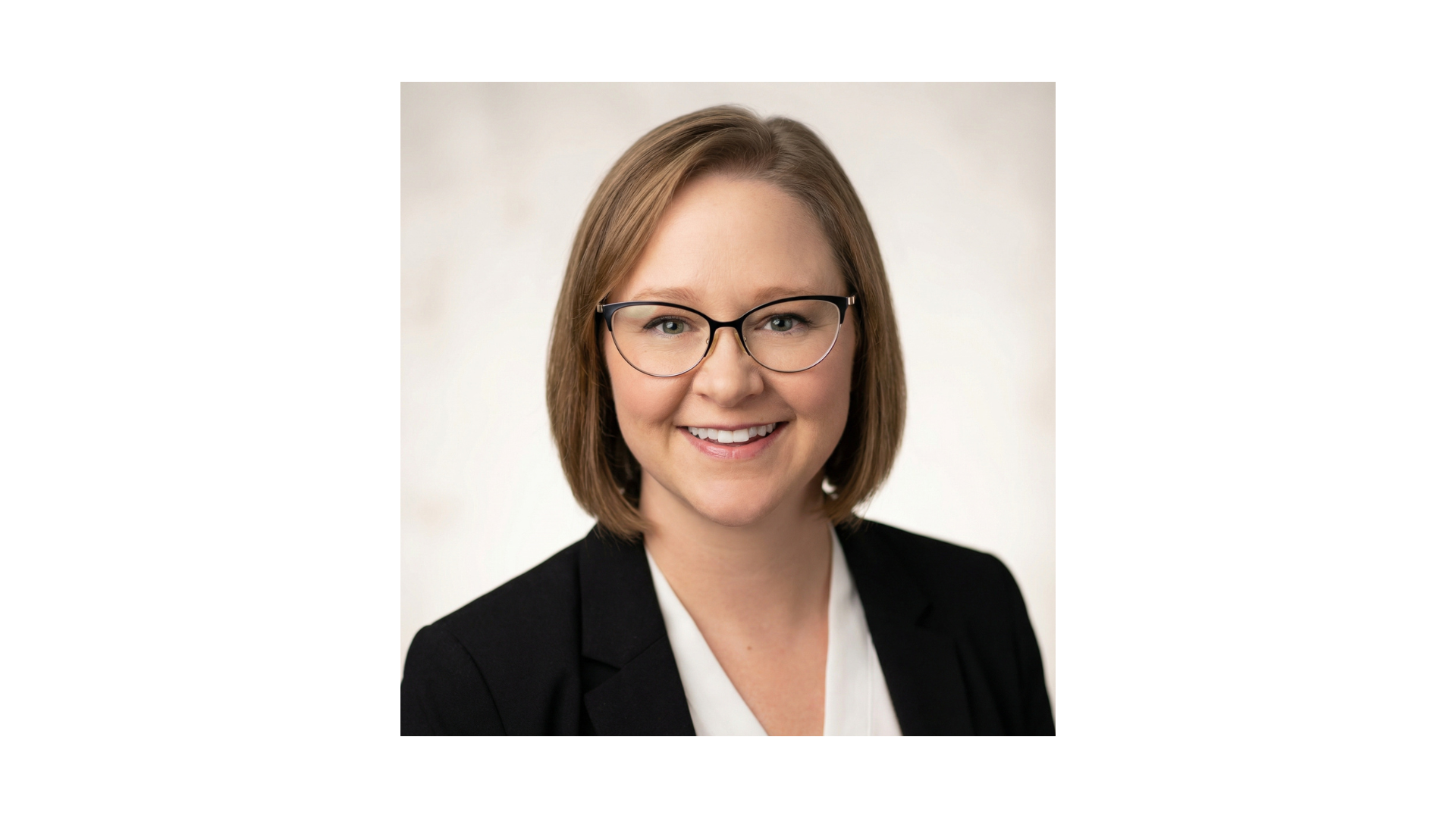 woman with short blonde hair wearing glasses and a black blazer