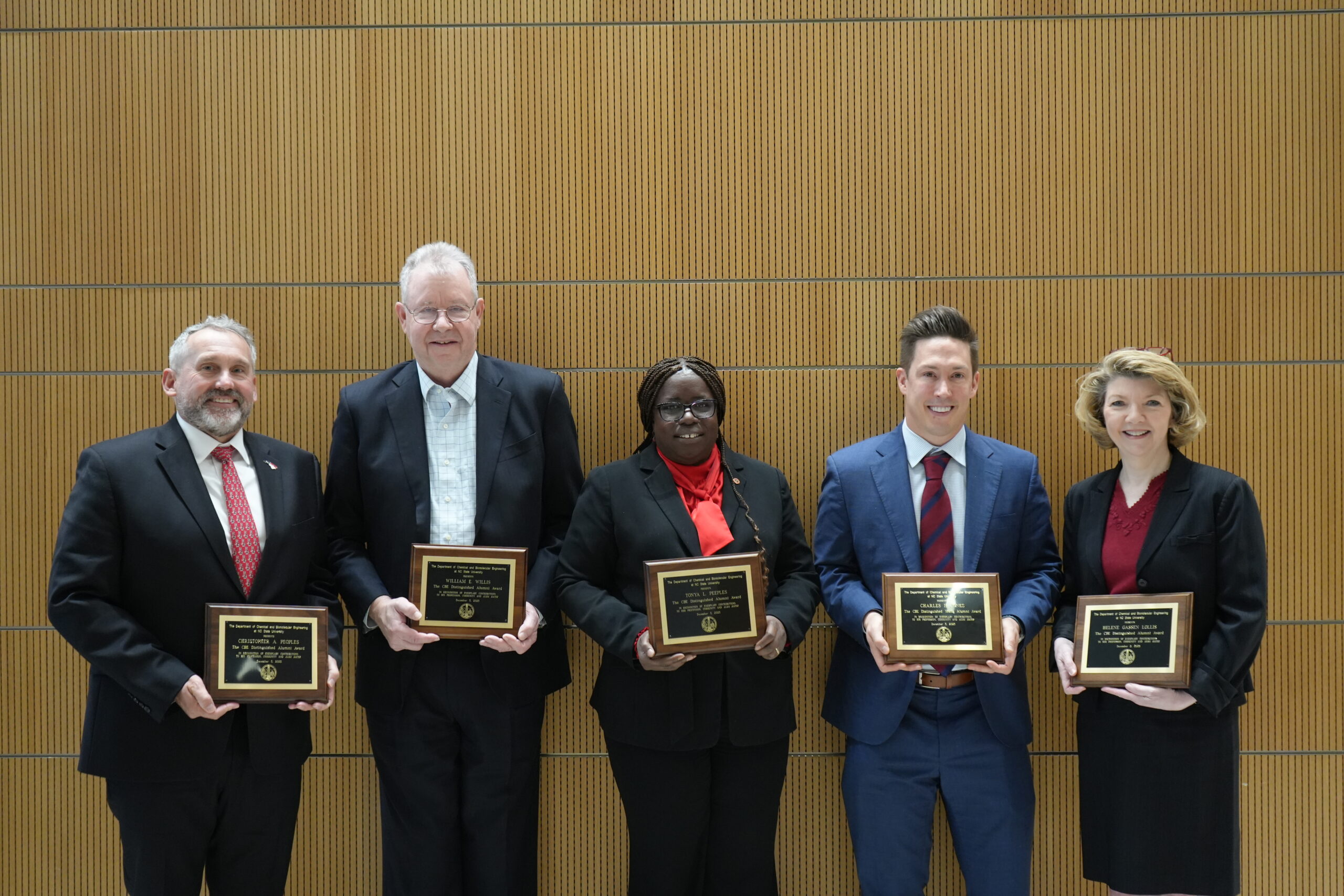 three men and two women smiling holding award plaques