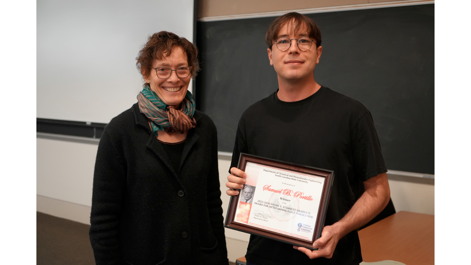 a person holding a framed award standing next to the presenter