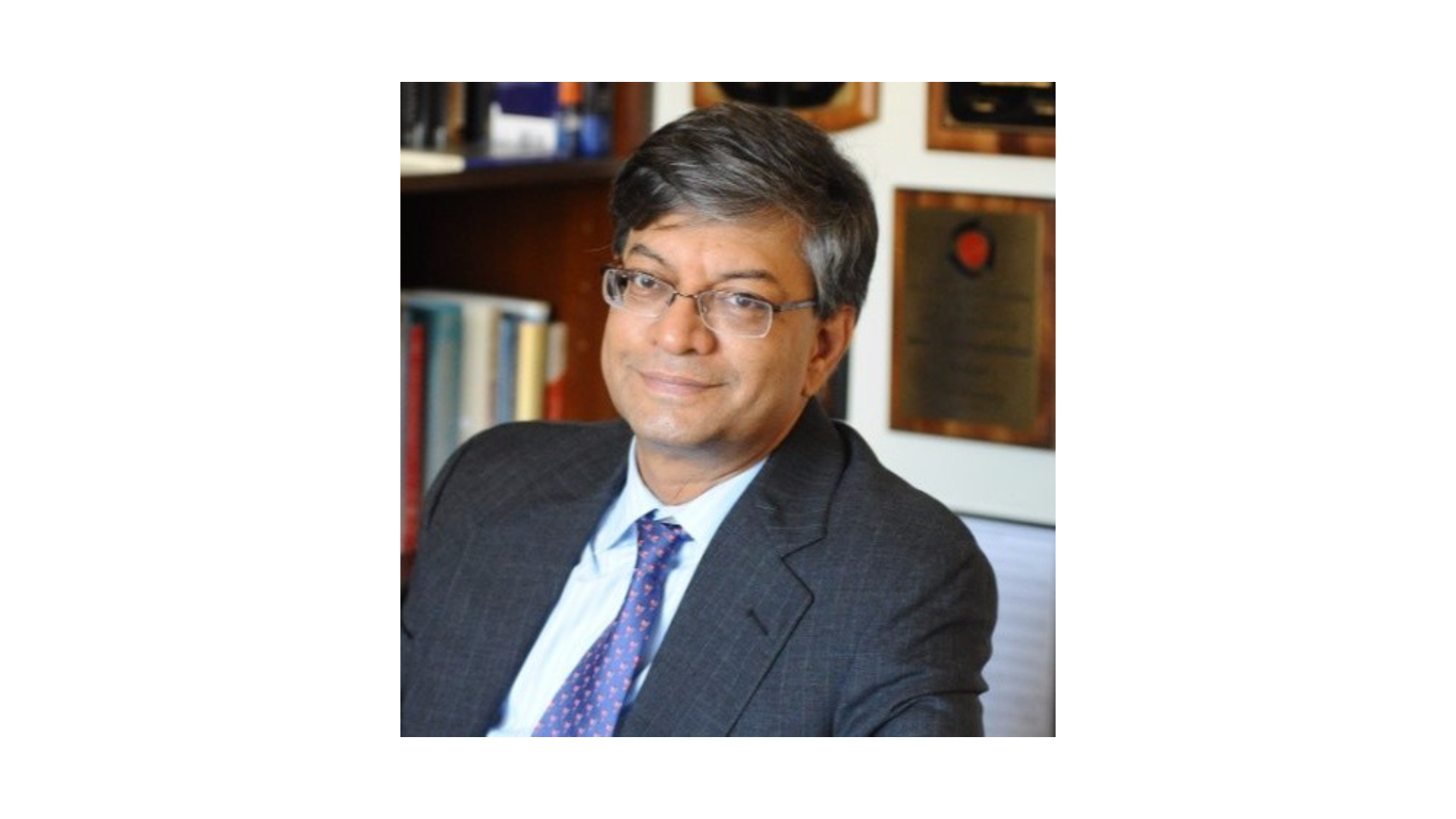 man with dark and gray hair wearing a suit and glasses