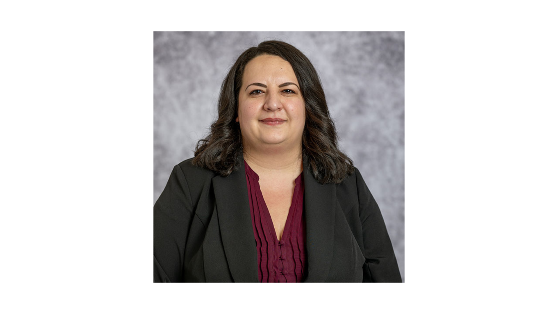 woman with short dark hair wearing a black blazer and purple shirt