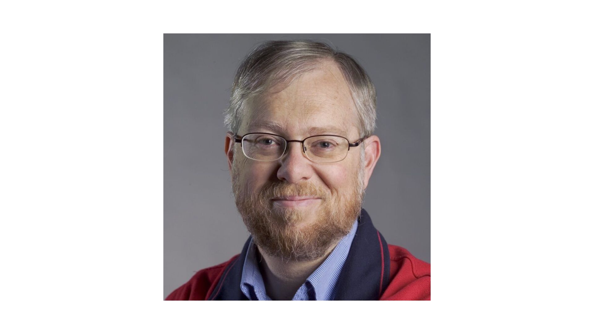 man with gray hair and red beard wearing glasses and a red sweater