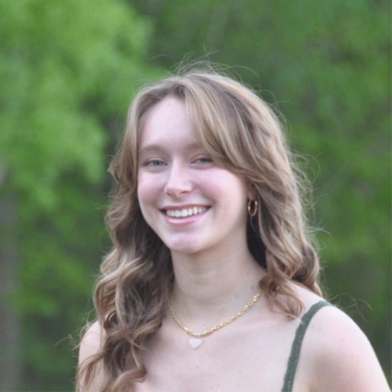 woman with long brown hair smiling outside